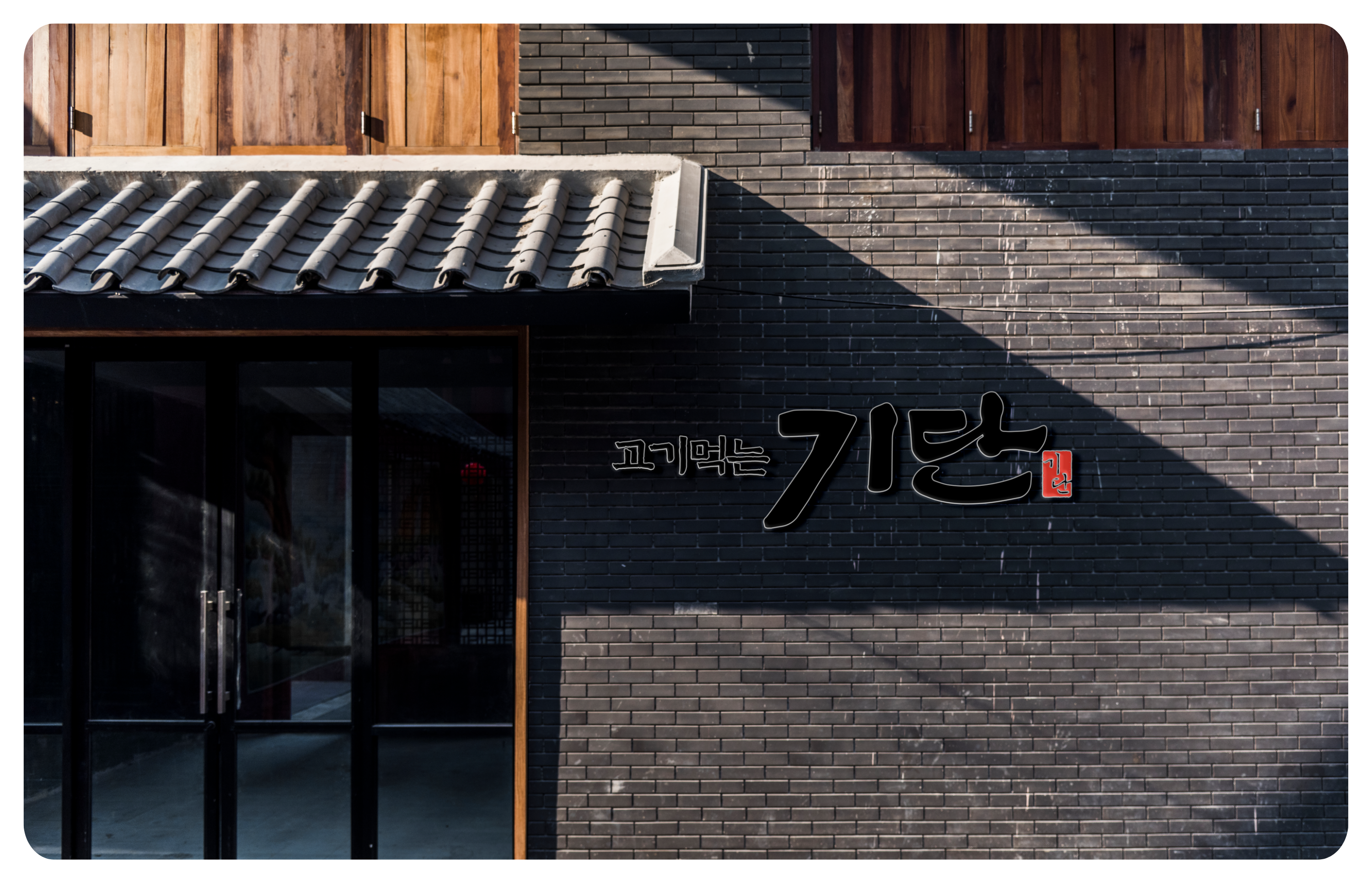 검은 벽돌 외벽에 간판이 걸린 건물 외관과 유리문 입구가 보인다.