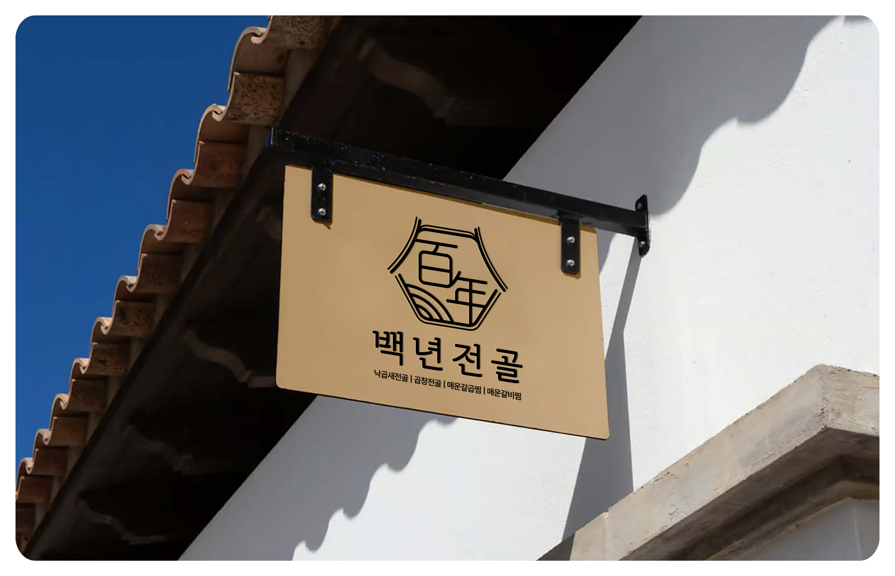 흰색 건물 외벽에 검은 브래킷으로 매달린 베이지색 간판